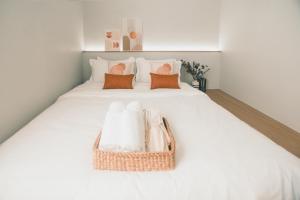 a white bed with a basket of towels on it at 41Cafetel Prachinburi in Prachin Buri