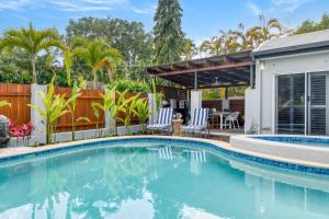 uma piscina com duas cadeiras e uma casa em Seabrook beach house em Port Douglas