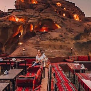 una mujer sentada en una silla frente a una pared de roca en WADI RUM STAR WARS CAMP en Wadi Rum