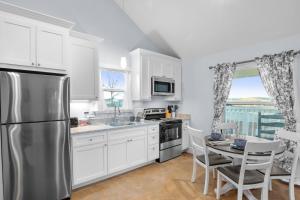 a kitchen with white cabinets and a stainless steel refrigerator at Appian Way Maltese Cottage in Fredericksburg