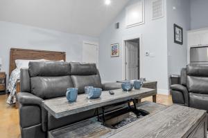 a living room with a leather couch and a table at Appian Way Maltese Cottage in Fredericksburg +22 photos