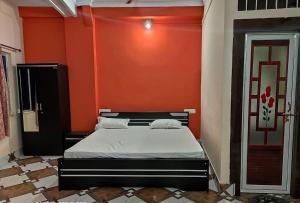 a bedroom with a bed with an orange wall at Hotel M.K. Palace in Gaya