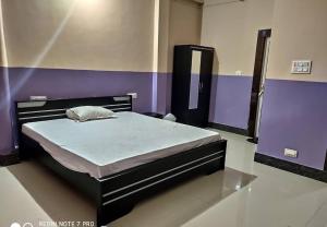 Cama en habitación con paredes moradas en Hotel M.K. Palace en Gaya