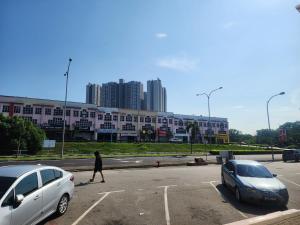 a person walking in a parking lot with two cars at BEAR HOTEL at NILAI in Nilai