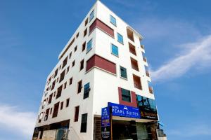 een groot wit en rood gebouw met een bord erop bij Pearl Suites - Located at a strategic location where Srinivasa Sethu Flyover starts and only hotel in the area to have a very spacious car parking - Skip city traffic to reach Main Temples and Airport - AC Rooms, Family Suites, Fast WiFi in Tirupati