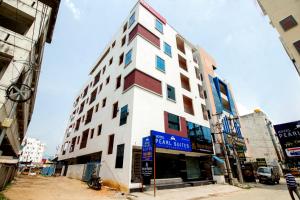 a tall white and red building on a city street at Pearl Suites - Located at a strategic location where Srinivasa Sethu Flyover starts and only hotel in the area to have a very spacious car parking - Skip city traffic to reach Main Temples and Airport - AC Rooms, Family Suites, Fast WiFi in Tirupati