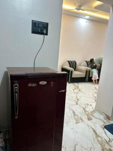 a little girl standing in a room with a clock on the wall at 1BHK Holiday Home in Nagpur