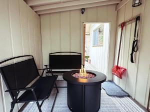 a screened in porch with a fire pit and two chairs at Álaínn Cabin in the trees in Twain Harte