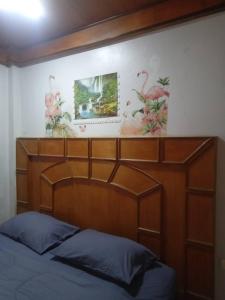 a bed with a wooden headboard and paintings on the wall at Maleeya garden guest house in Ko Chang