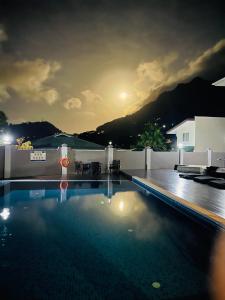 a swimming pool at night with the moon in the sky at D'Offay Seaview Apartments in Beau Vallon