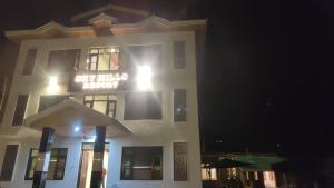 un bâtiment blanc avec un panneau sur lui la nuit dans l'établissement SKY HILLS RESORT, à Pahalgām