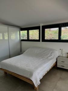 a white bedroom with a bed and windows at Saloniky Garden in H̱olon