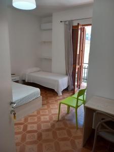 Habitación con 2 camas y una silla verde. en Dimora degli Enotri en Scalea