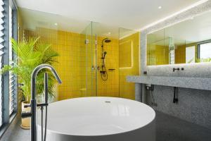 a bathroom with a tub and a shower with yellow tiles at Stupid Stay in Bangkok