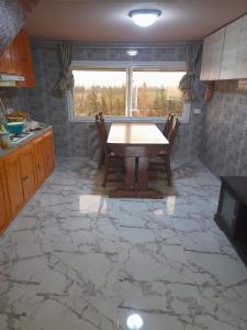 a kitchen with a table and chairs on a stone floor at Maison de campagne à 20mn du centre ville Tunis in Mornag