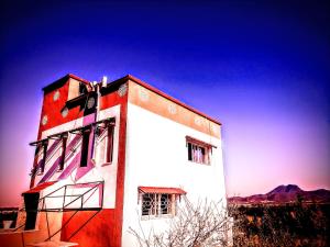 un edificio rojo y blanco con una montaña en el fondo en Maison de campagne à 20mn du centre ville Tunis, en Mornag