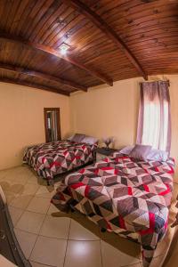 two beds in a room with a wooden ceiling at Casa Luna in Quetzaltenango