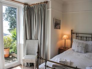 a bedroom with a bed and a chair and a window at The Keel Row in Salcombe