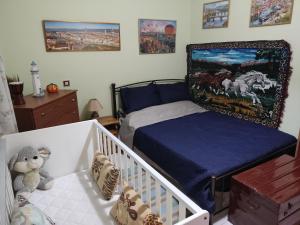 DIMITRIS EYRIAKIS COTTAGE في ميتيليني: غرفة نوم مع سرير أطفال ولوحات على الحائط