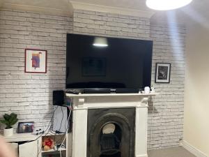 TV de pantalla plana en una pared de ladrillo con chimenea en Stay with Light en Ipswich