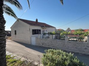 a white house with a stone wall and a fence at Holiday Home Kristin in Mirce