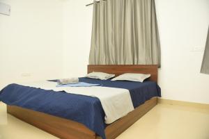 a bedroom with a bed with blue and white sheets at Sai Homestay Panaji 2 BHK and Studio Apartment in Panaji