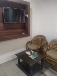 達蘭薩拉的住宿－Ravine hights，客厅配有两把椅子、一张桌子和电视