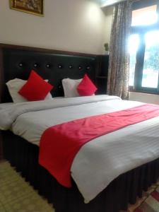 a bedroom with a large bed with red pillows at Ravine hights in Dharamshala