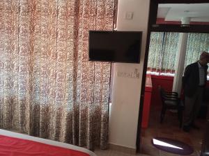 a room with a tv and a curtain at Ravine hights in Dharamshala
