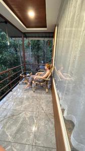 Una donna seduta su una sedia in veranda di Cave Valley Wayanad ad Ambalavayal