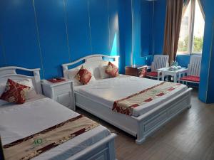 2 camas en una habitación con paredes azules en Nhat Quy Hotel, en Tây Ninh