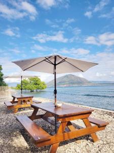 two picnic tables with an umbrella on a beach at Bruri Villa in Alor-kecil