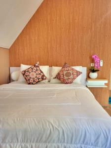 um quarto com uma cama branca com almofadas em Bruri Villa em Alor-kecil