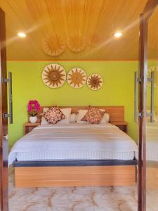 a bedroom with a large bed with green walls at Bruri Villa in Alor-kecil