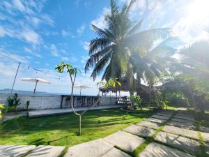 a house with a palm tree next to the ocean at Bruri Villa in Alor-kecil