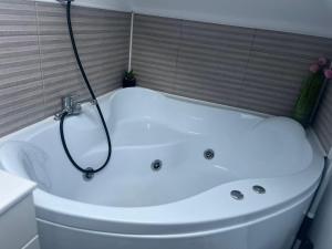 uma banheira branca com um chuveiro na casa de banho em Apartament Mansarda Venus em Râmnicu Vâlcea