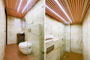 a bathroom with a toilet and a glass shower at Staybook South Delhi in New Delhi