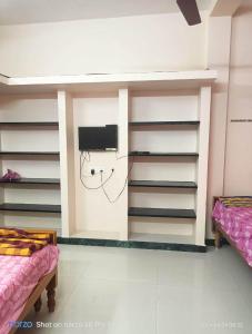 Habitación con 2 camas y TV en la pared. en KG Homes, en Chidambaram