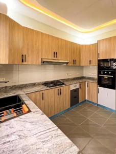 eine große Küche mit Holzschränken und -geräten in der Unterkunft Luxury Oasis 1 - Private En-suite 1 Bedroom in a Shared Apartment in Abuja with Pool, Games, Balcony, and Garden in Abuja