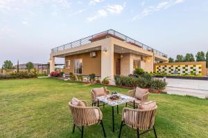 Alaya Heaven in Hills Luxe 2BHK Villa with Pvt Pool, Udaipur في أودايبور: منزل به طاولة وكراسي في الفناء