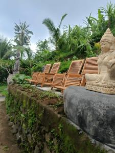 un grupo de sillas y una estatua delante en BAMBOO OASIS en Ubud