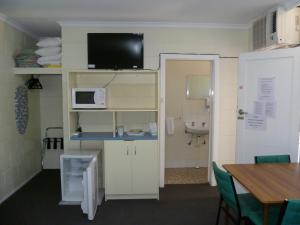 um quarto com uma cozinha com uma mesa e um micro-ondas em Norfolk Motor Inn em Adelaide