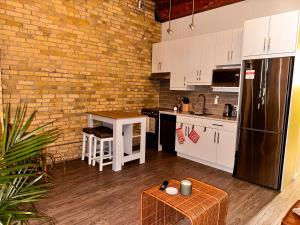 Heart of the City: Cozy 2-Bed Loft في وينيبيغ: مطبخ بدولاب بيضاء وجدار من الطوب