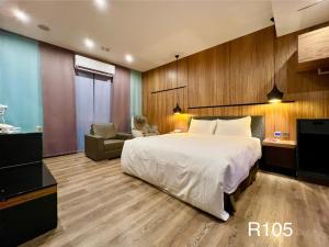 um quarto com uma cama grande e uma cadeira. em Catwalk Motel -Tainan em Tainan