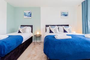 two beds in a room with blue and white at Relaxing 4 Bedroom Retreat For Long Stays Fawley in Totton