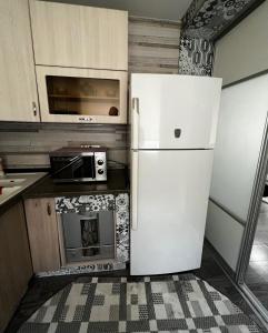 a white refrigerator in a kitchen with a fireplace at Ахметова 12 in Almaty