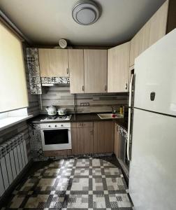uma cozinha com armários de madeira e um frigorífico branco em Ахметова 12 em Almaty
