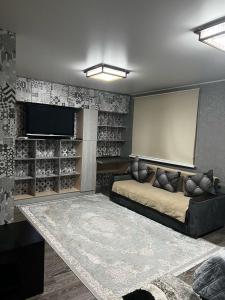 a living room with a couch and a flat screen tv at Ахметова 12 in Almaty