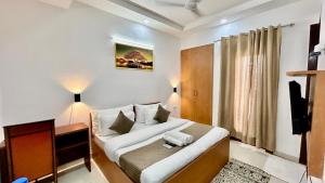 een slaapkamer met een bed, een bureau en een televisie bij Aura Luxury Studio Near Golf Course Road, Sector 57, Gurgaon in Gurgaon