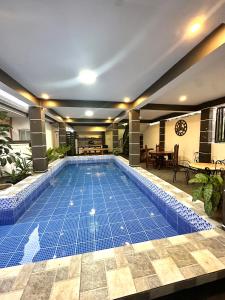 a large swimming pool with blue tiles in a building at Sts. Joachim and Ann Staycation house in Ulot